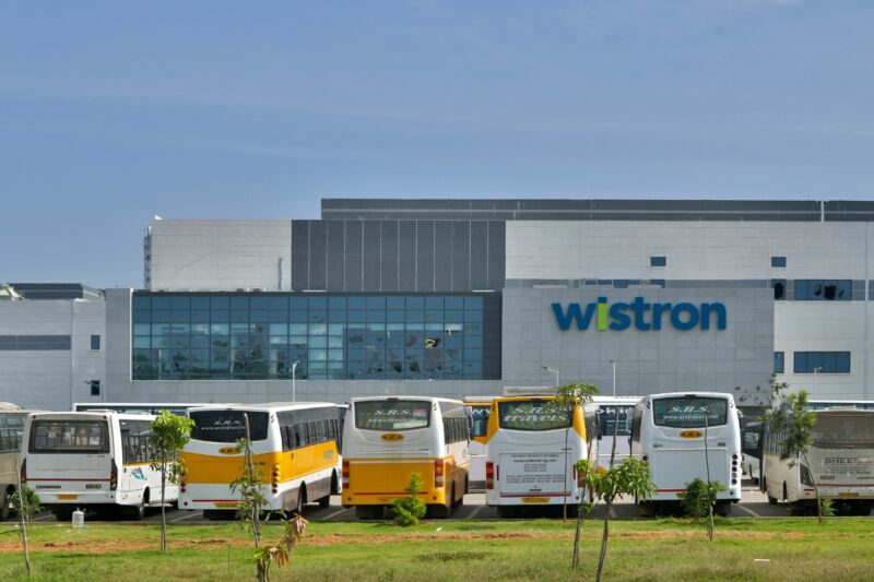 Busses surround a wide building of glass and steel.