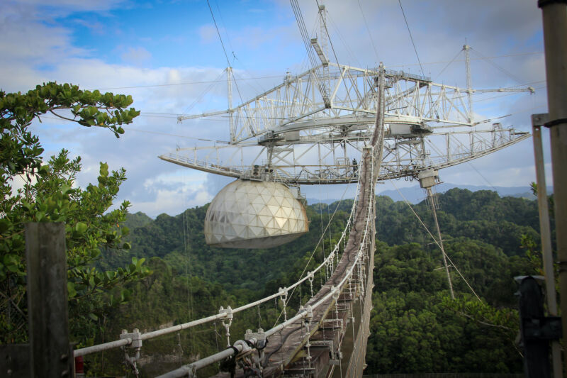 Image of a large dome suspended from a metal lattice hanging from cables.