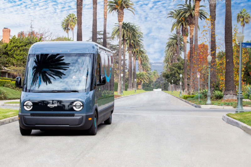 An Amazon-branded truck drives down a street lined with palm trees.