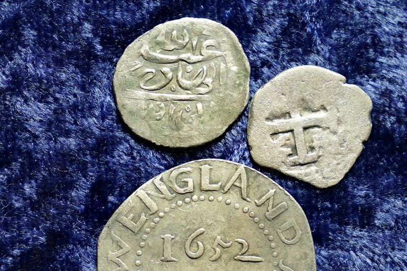 Extreme close-up photo of centuries-old coins on blue velvet.