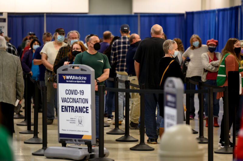 Masked crowds wait in cordoned lines.