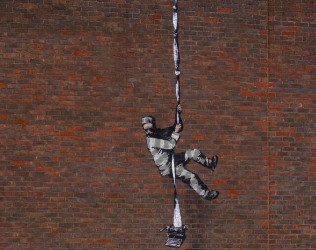 Art work by graffiti artist Banksy, depicting a prisoner escaping with a typewriter—a tribute to one of its famous former prisoners, Oscar Wilde—in Reading, England.