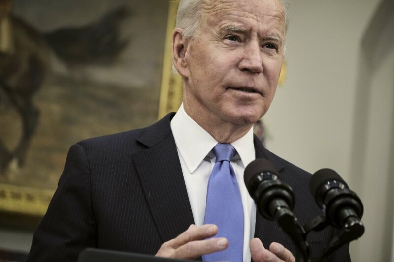 President Joe Biden standing and speaking in front of microphones.