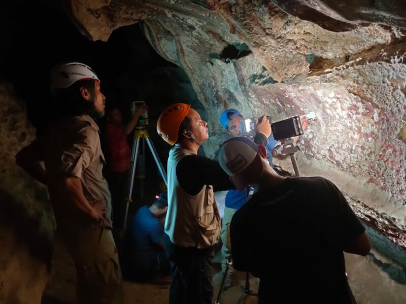 color photo of archaeologists examining rock art in a dark cave