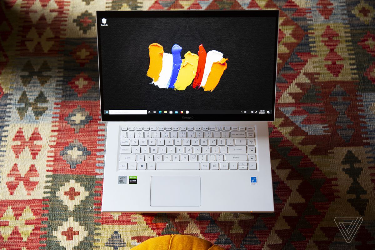 The Acer ConceptD 7 Ezel open, seen from above, on a patterned carpet. The screen displays a few colored paintbrush strokes on a black background.