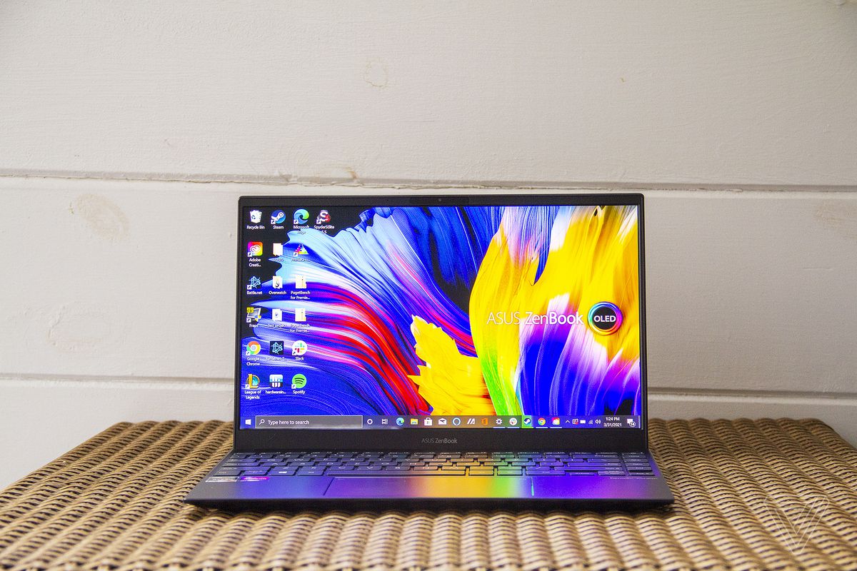 The Asus Zenbook 13 OLED seen from the front. The screen displays Zenbook and OLED logos on a multicolor background.