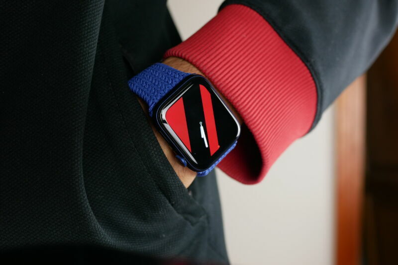 Extreme close-up photograph of a wristwatch on a hand in a pants pocket.