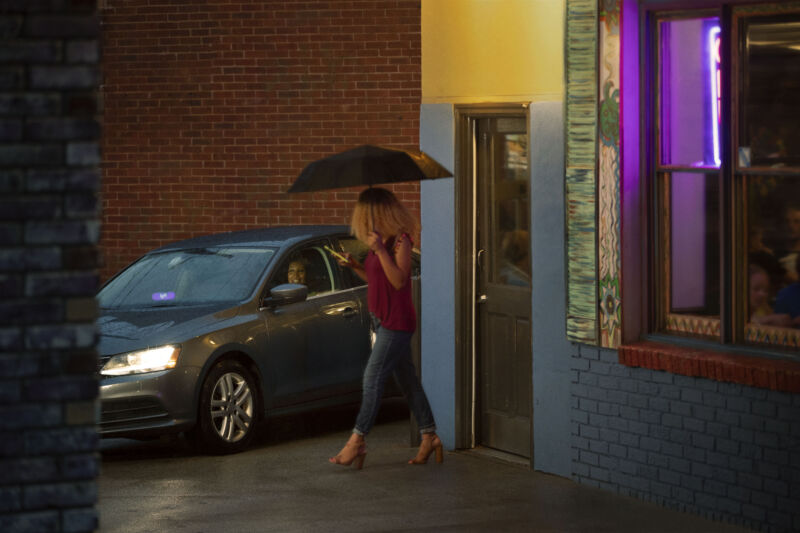 A woman in an umbrella walks to her Lyft.