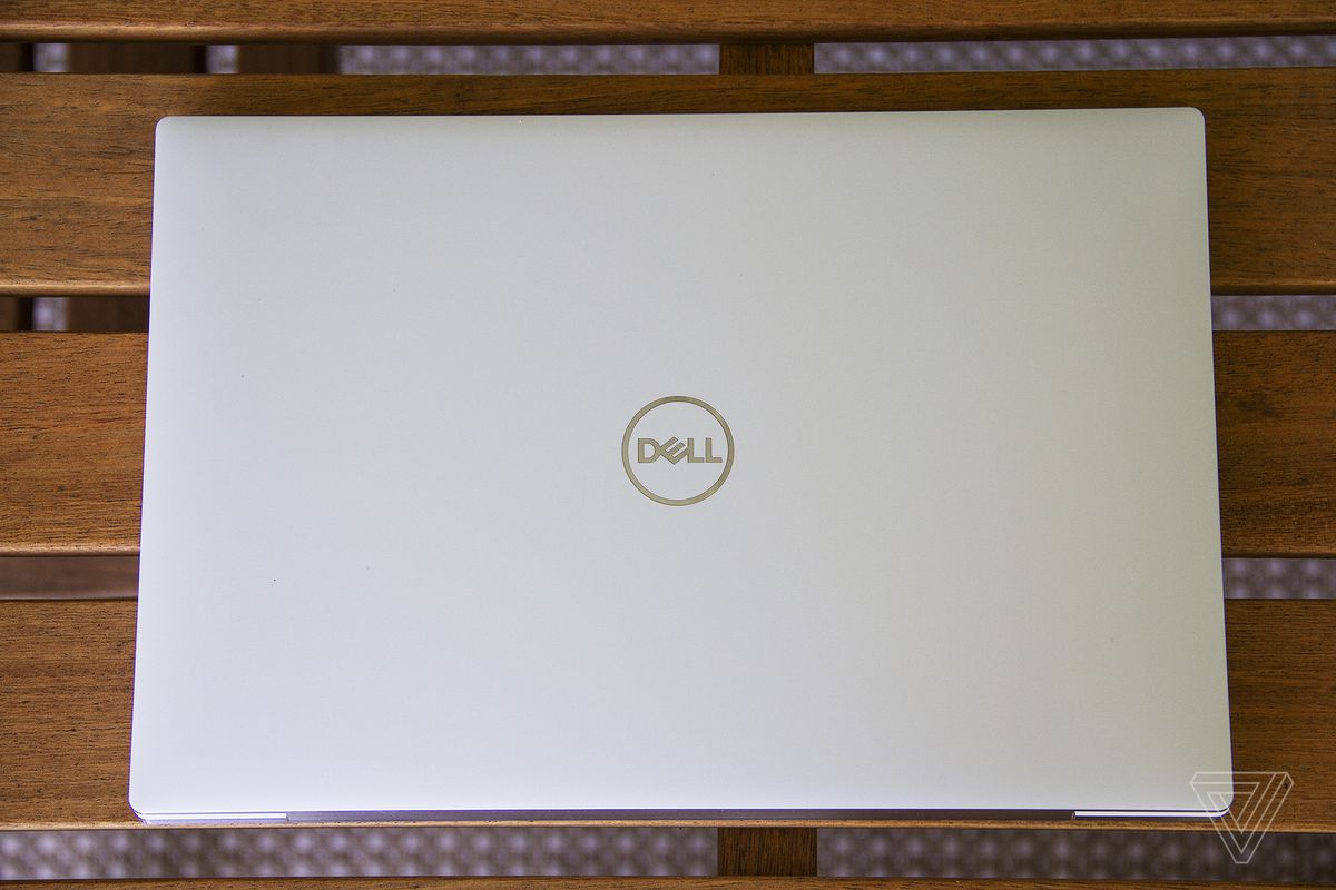 The Dell XPS 13 OLED lid on a wooden table seen from the top.