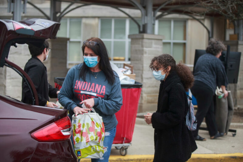 Image of masked parents and students near a car.