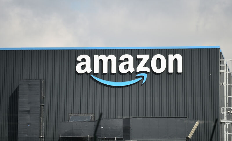 Outside view of a warehouse with a large Amazon logo on the side of the building.