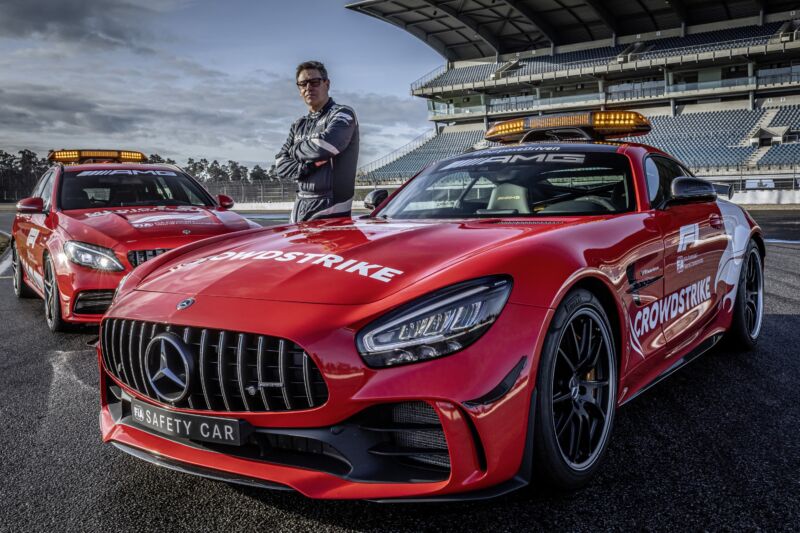 Bernd Maylander stands next to the F1 safety car and the F1 medical car