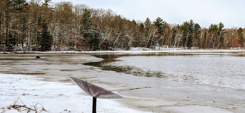 A Starlink satellite dish sitting next to a lake in a remote area.