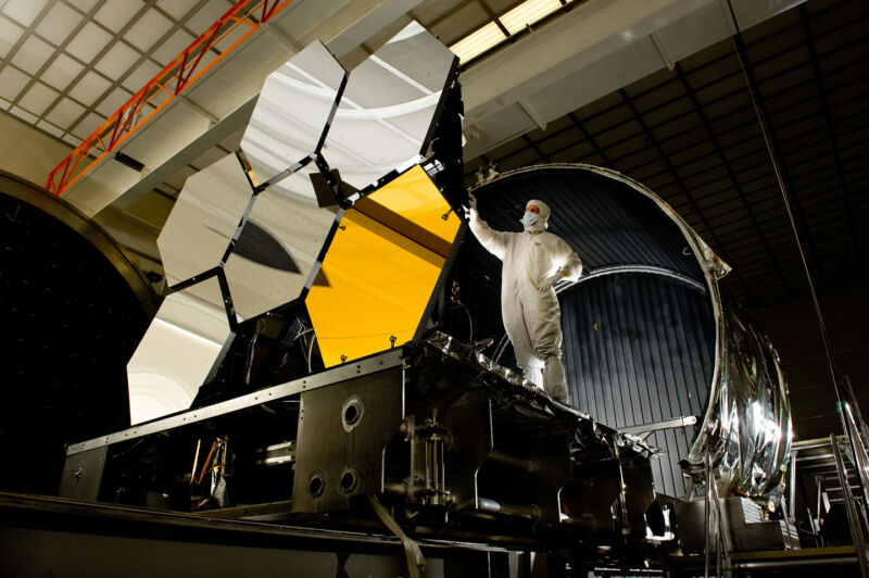 Image of a person next to a set of hexagonal mirrors.