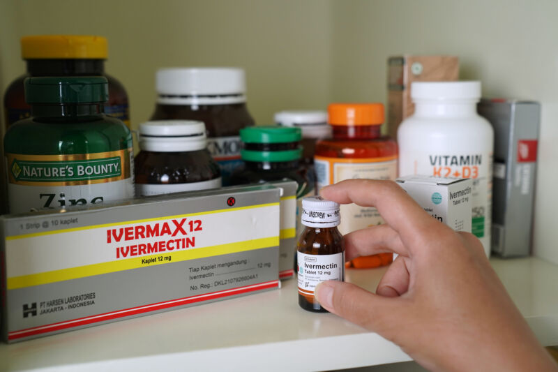 Close-up photograph of hand rooting around medicine cabinet.