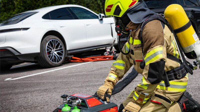 To put out an EV blaze, a firefighter operates the nozzle from a remote control box.