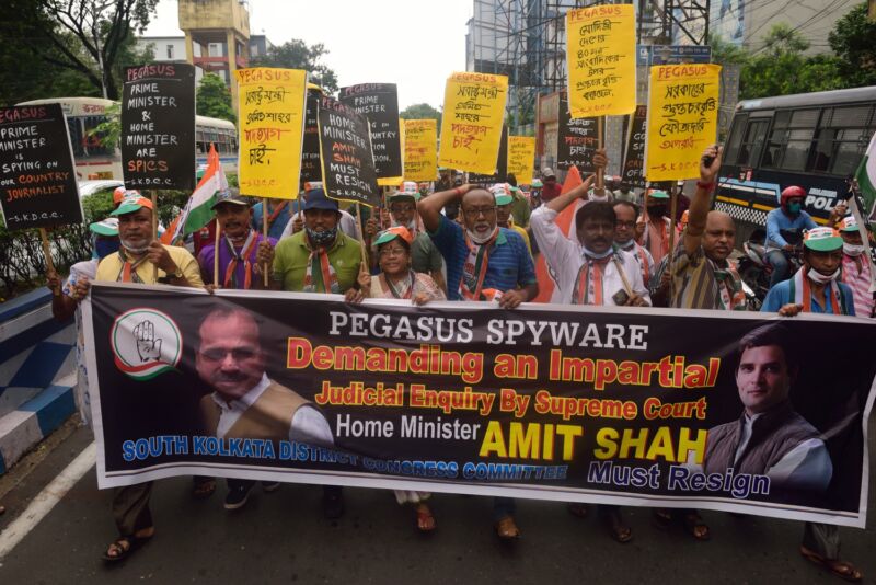 Protesters in India hold signs criticizing the Indian government's use of Pegasus spyware.