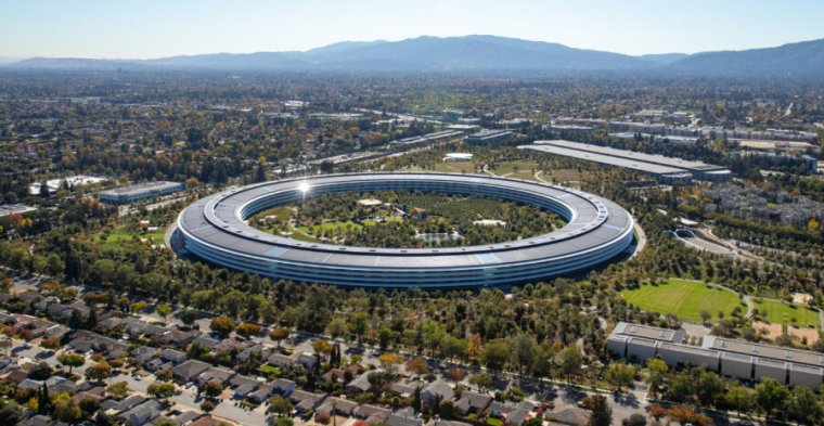 An enormous ring-shaped building on a green campus.