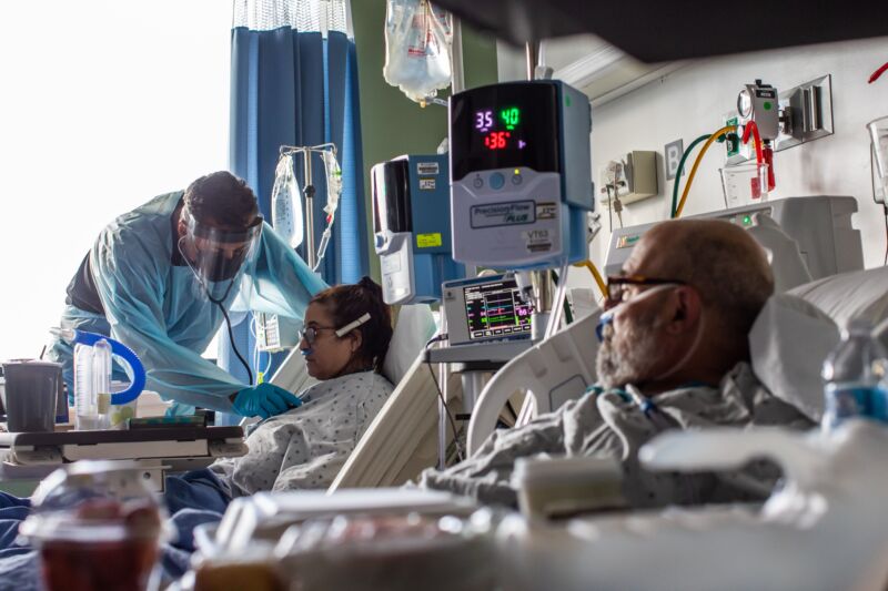 Doctor in protective gear inspects patients.