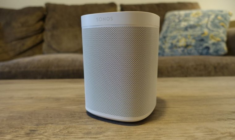 A white speaker sits on a wooden coffeetable.