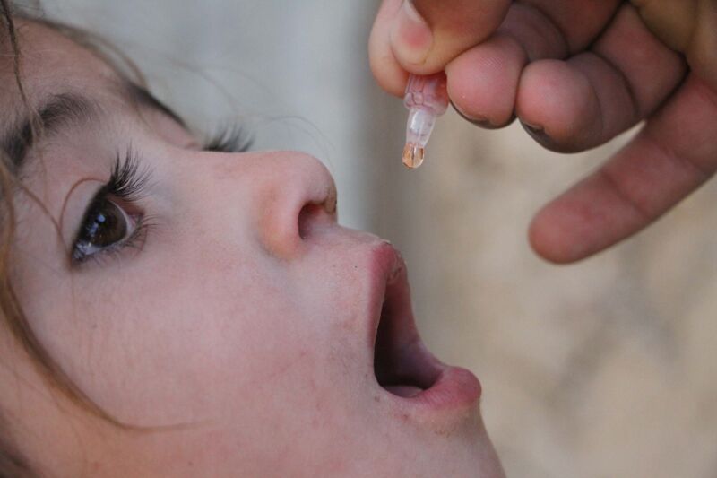 A health worker administers a polio vaccine to a child out of Kabul Afghanistan on May 17, 2016. 