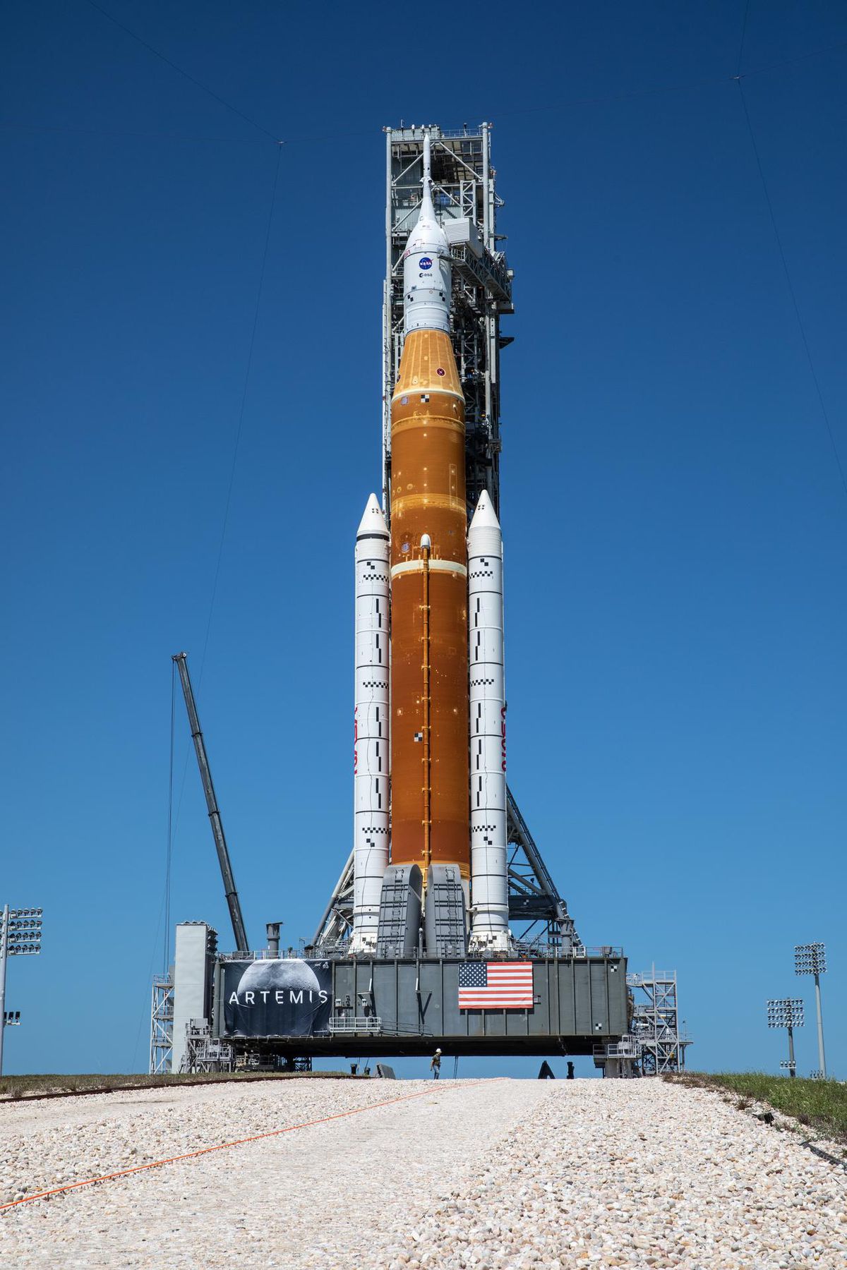 The SLS rocket on a large platform with a rocky road in the foreground.