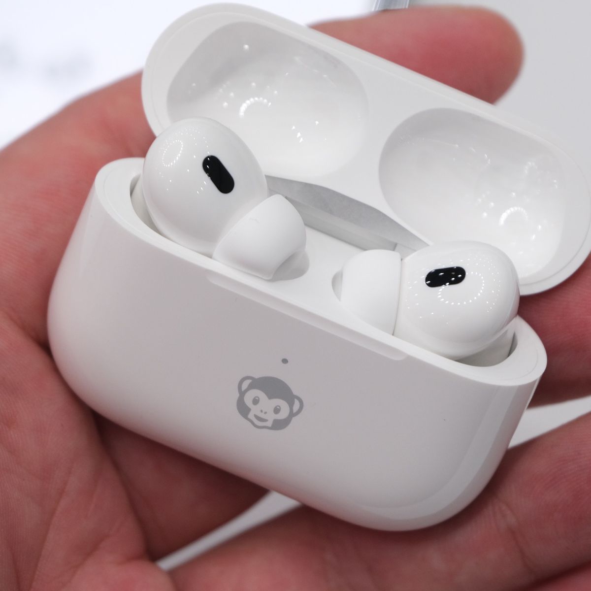 A hand holding Apple’s second-gen AirPods Pro inside of its charging case.