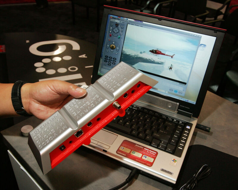 The original Slingbox, on display at the 2006 Consumer Electronics Show. Key indicators this was a long time ago include the Toshiba Satellite laptop used for the demonstration (and the giant glossy UI buttons).