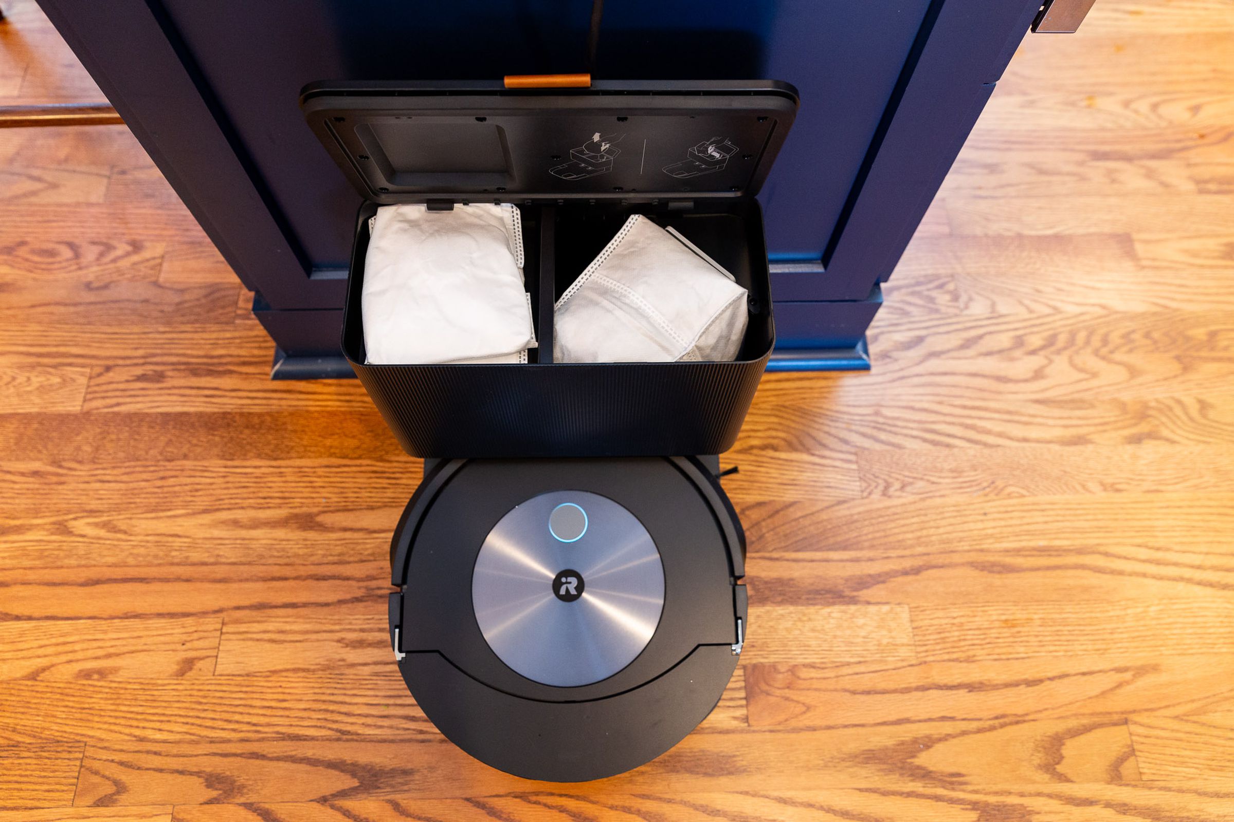 Top-down shot of the Roomba’s auto empty base with the lid lifted.