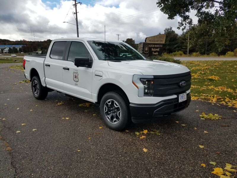 A White Ford F-150 Lightning with US Forest Service badges on the doors.