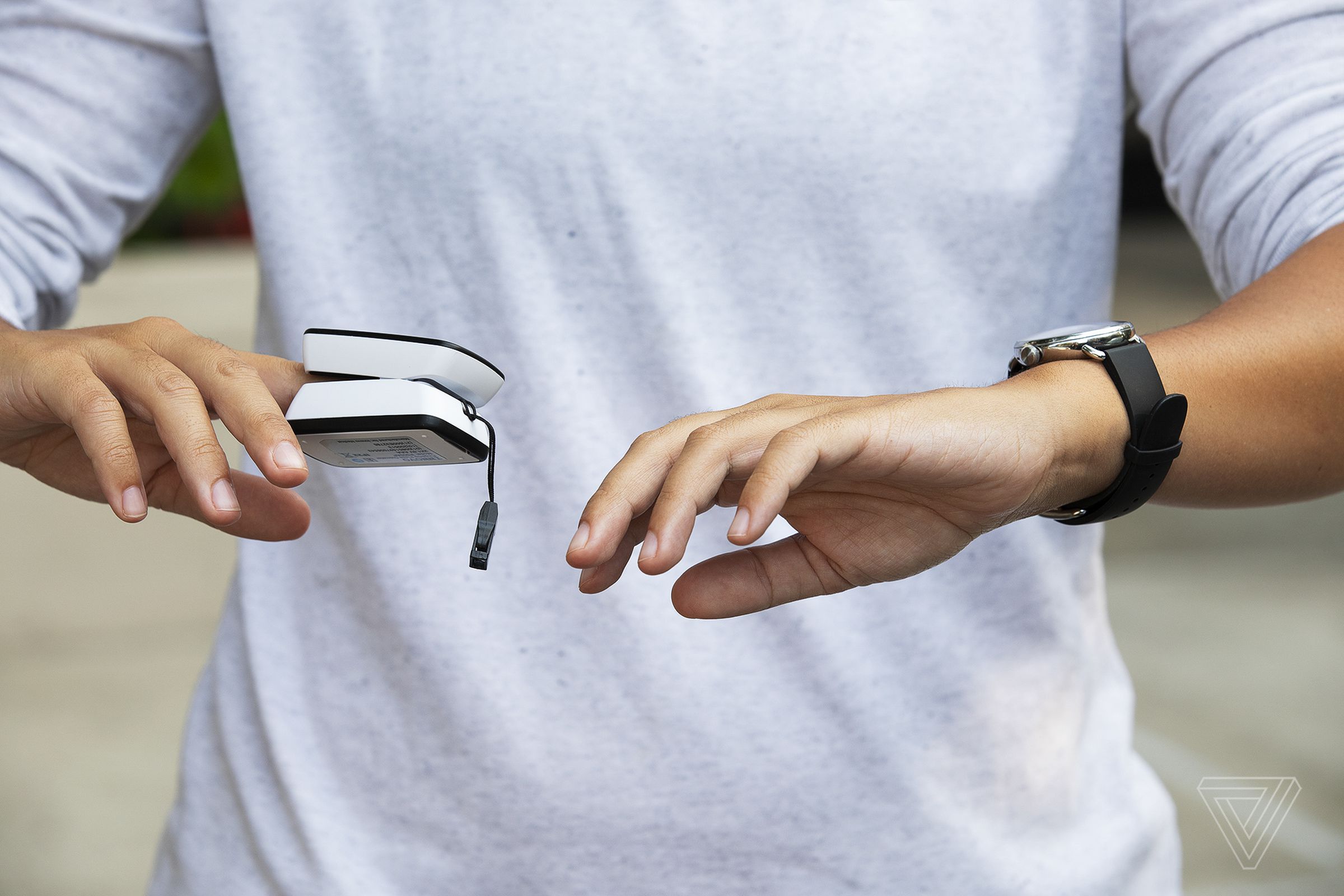 A person measuring SpO2 with both a fingertip pulse oximeter and the Withings ScanWatch.