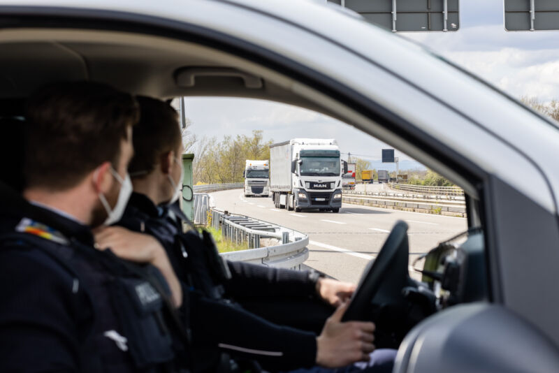 German police sit in their car off the highway while watching moving traffic