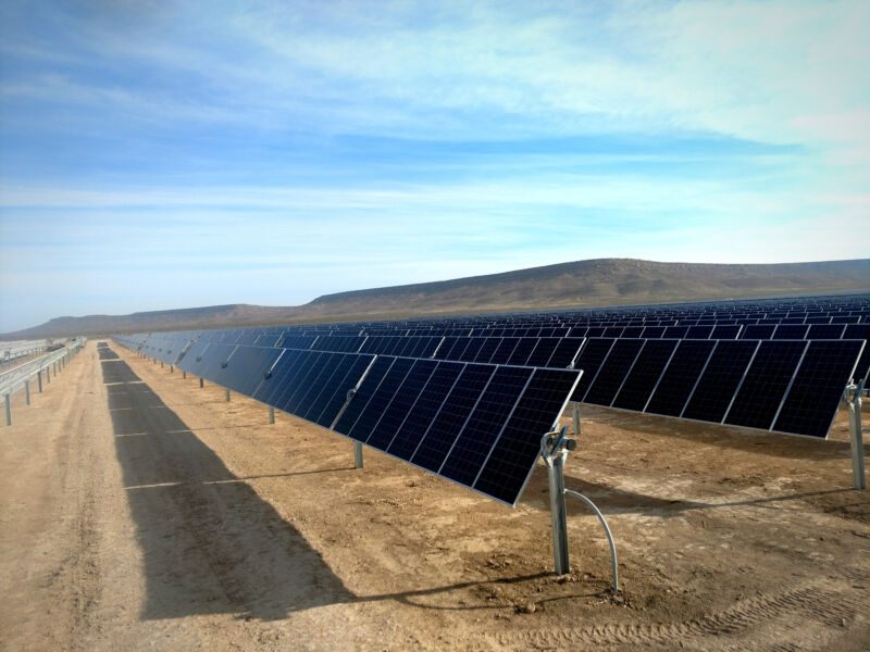 Image of solar panels in a dull brown desert.