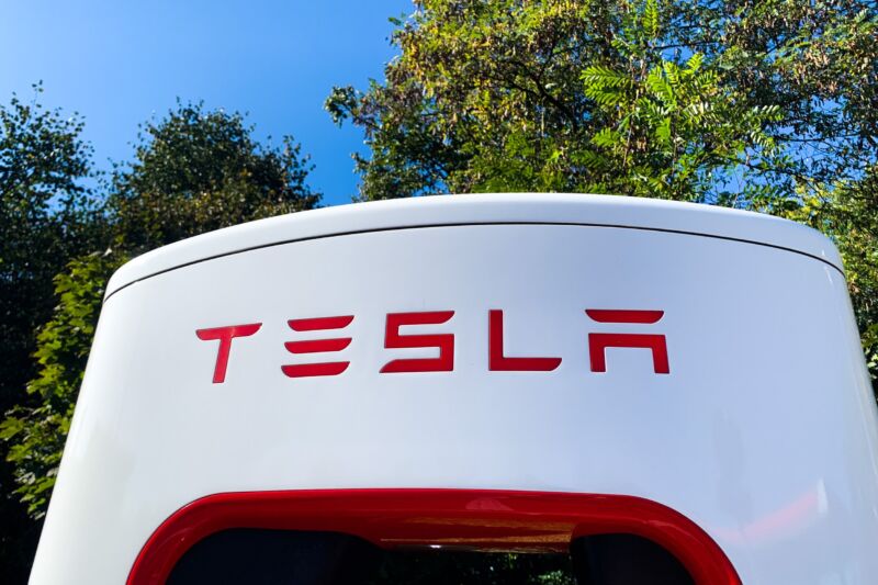 A Tesla logo seen on a charging station outdoors during daytime.