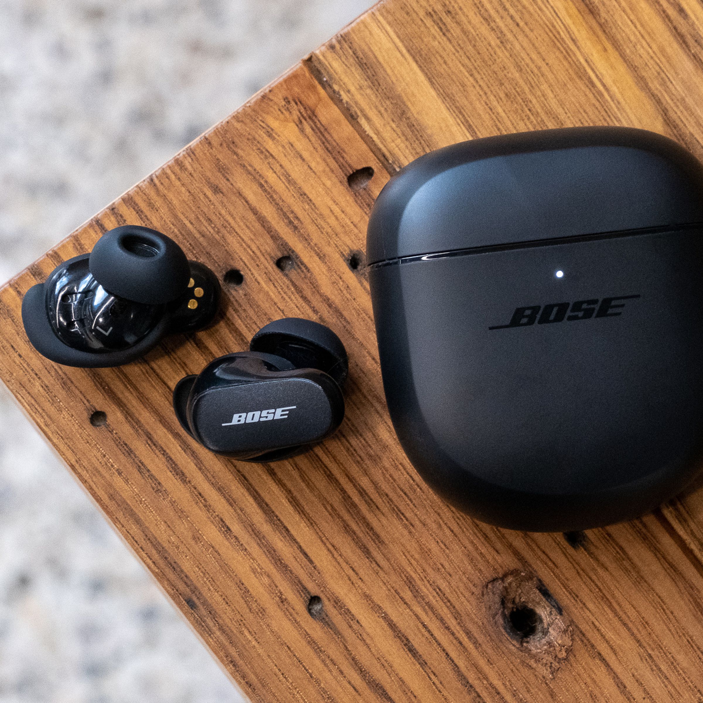 An overhead image of the Bose QuietComfort Earbuds II on a wood table.