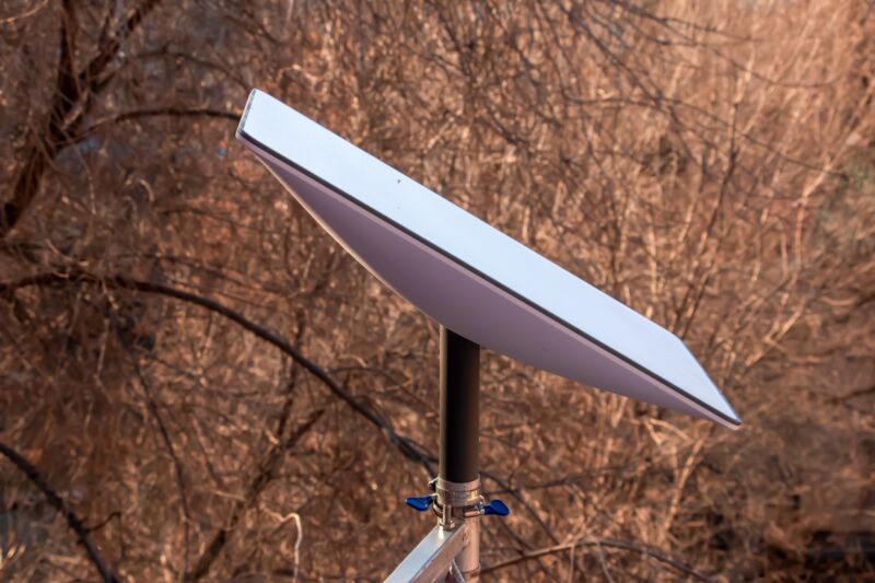 A Starlink satellite dish seen with trees in the background.