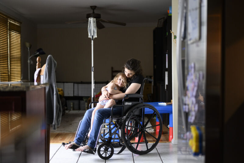 A long COVID patient sits with her daughter in her wheelchair while receiving a saline infusion at her Maryland home on Friday, May 27, 2022. 