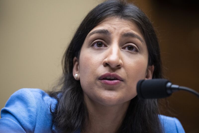 FTC Chair Lina Khan sits at a table and speaks into a microphone during a congressional hearing.