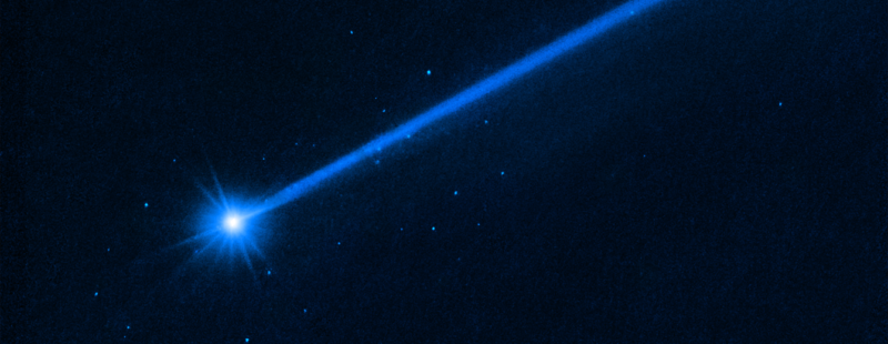 A blue streak runs diagonally across a black background, with a brighter blob at the end of the streak in the lower left.