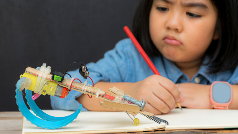 An enthusiastic elementary school pupil studying a robot.