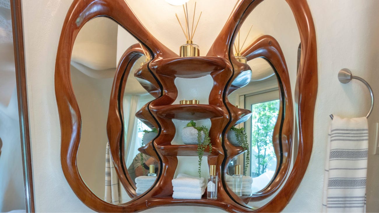 Wood-carved bathroom sink mirror in the shape of two elephant ears.