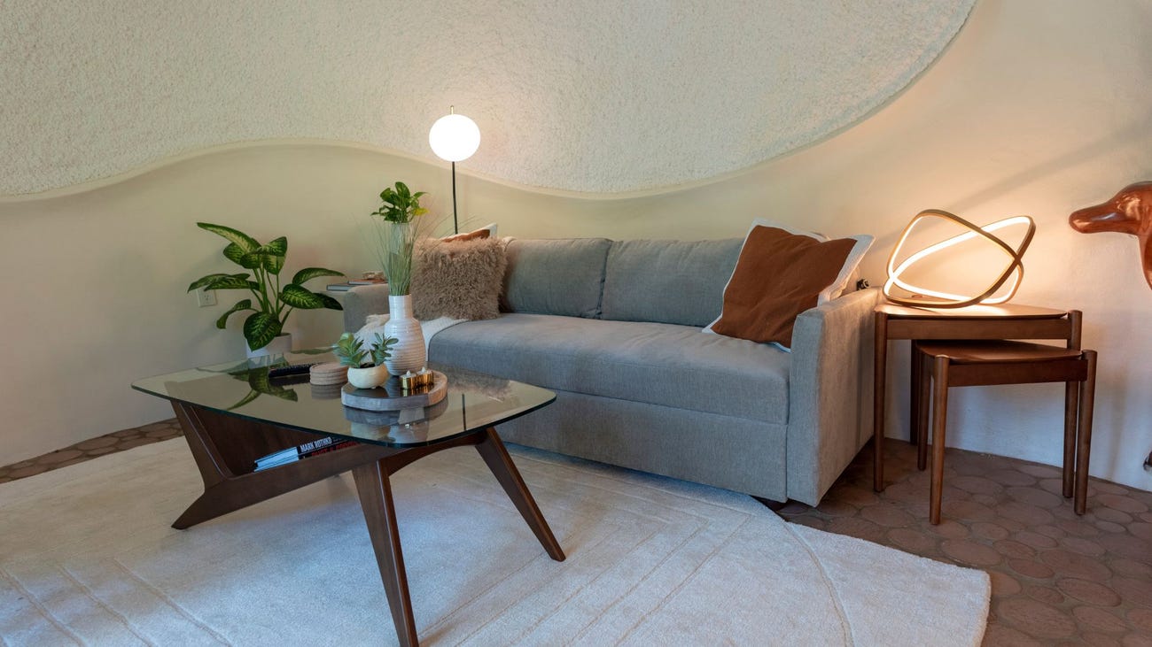 A comfy grey sofa and mid-century modern coffee table, side table, and decor in the Bloomhouse living room.