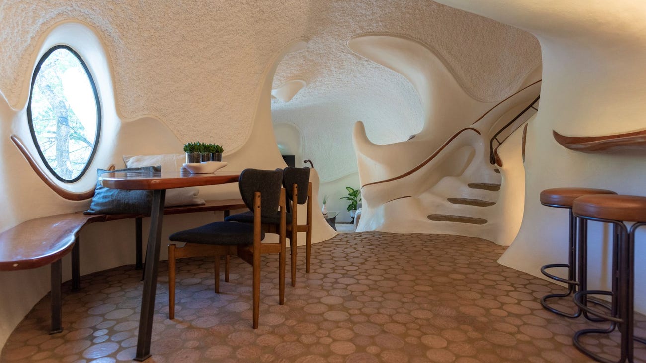 The Bloomhouse foyer with a small desk, chairs, stools and a round window.