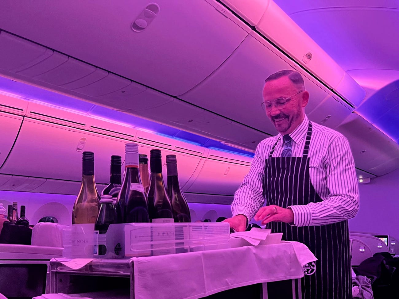 A flight attendant behind the food and drinks cart.