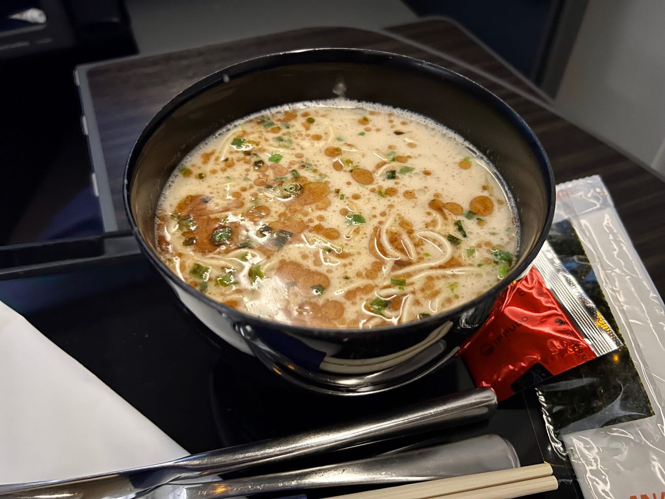 A black plastic bowl of filled with ramen noodles.