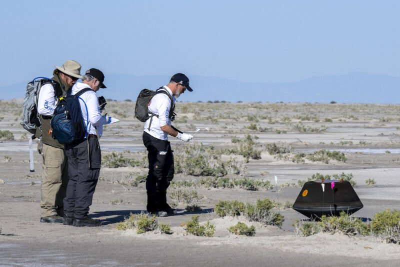 Dante Lauretta (right), OSIRIS-REx principal investigator, approaches the sample return capsule Sunday at the Utah Test and Training Range.