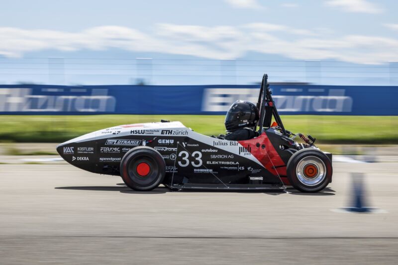 a small electric single-seat race car accelerates on a runway