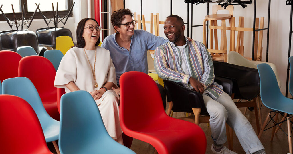 (L-R): Jiah Choi, Brandon Henderson and Marques Gartrell sit in a room full of red and blue chairs