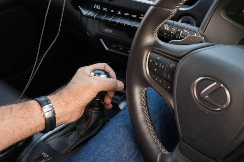 A man's hand operates the gear lever in a Lexus EV