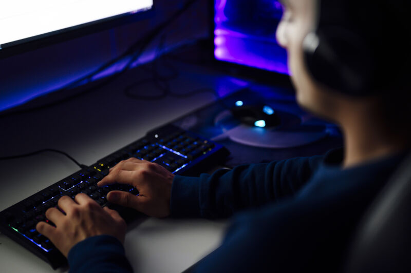 Gamer with headphones playing a PC game in a dark room